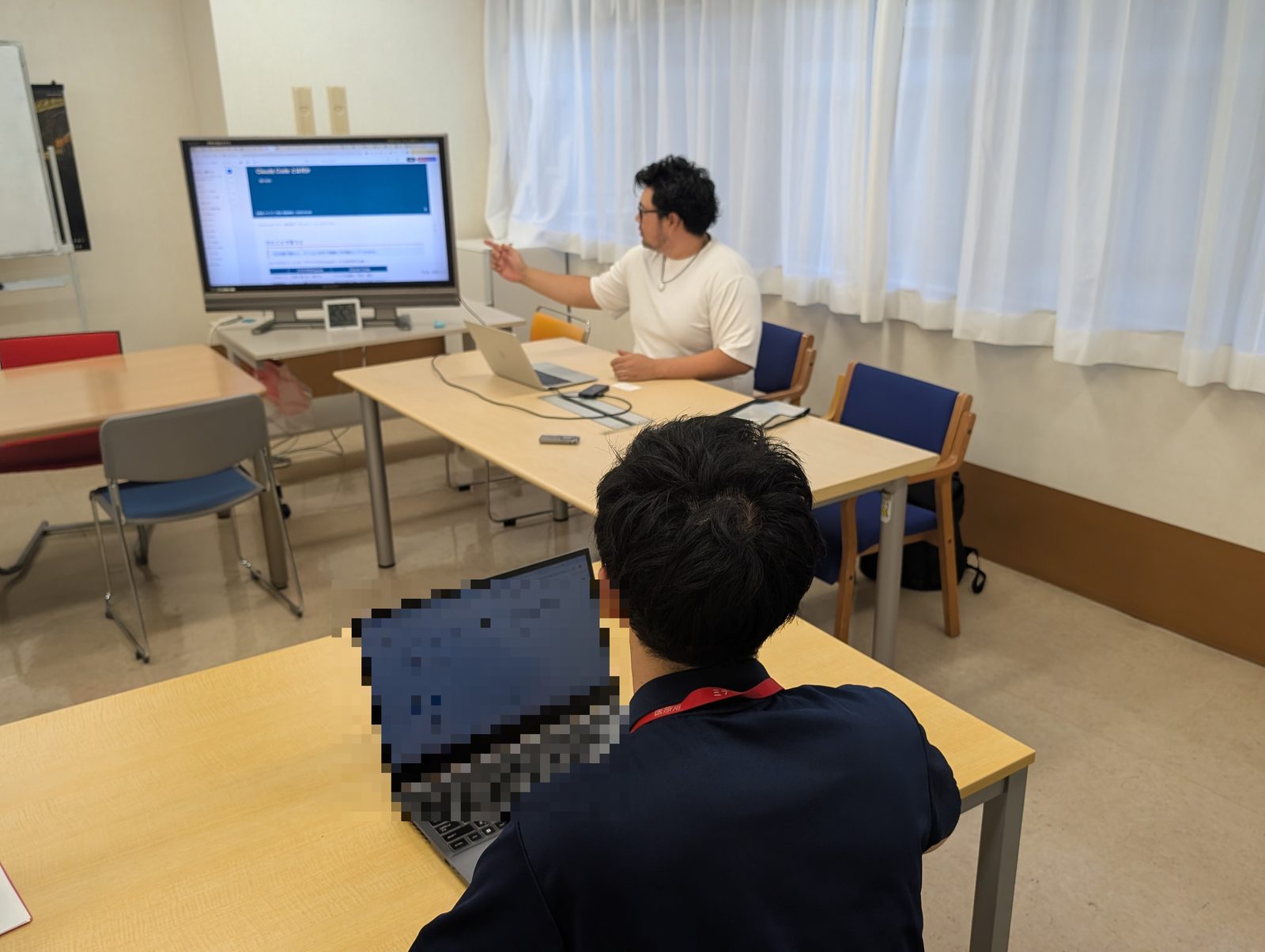福祉施設で、合同会社サンの代表が職員に画面を示しながら、AIの具体的な使い方を説明している様子
